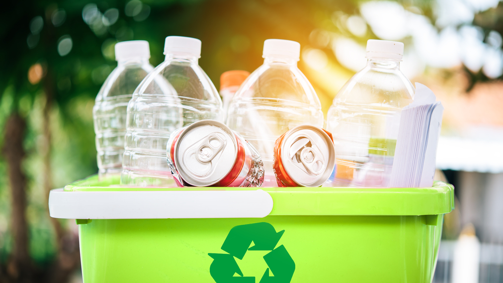 cans and plastic bottles in a basket with a recyclable icon in front